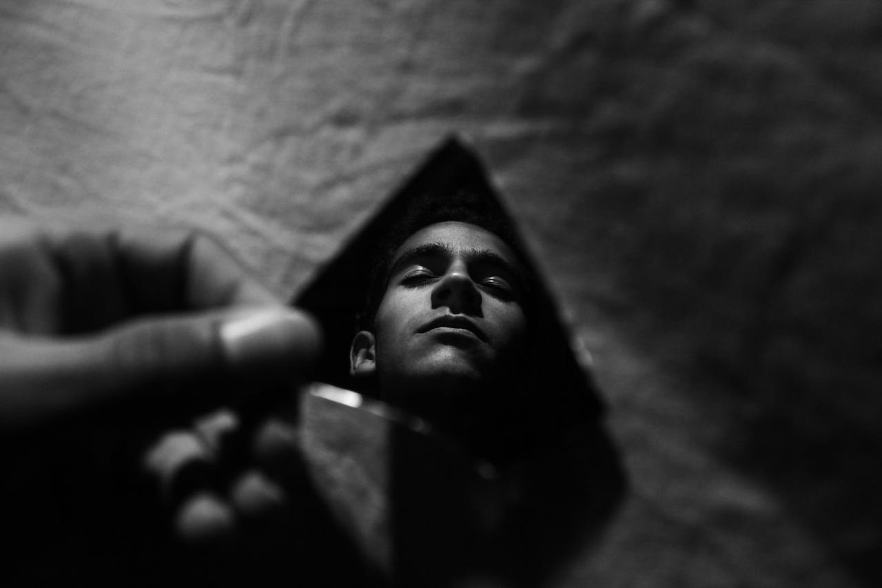 A moody black and white portrait reflection captured in a broken piece of glass.